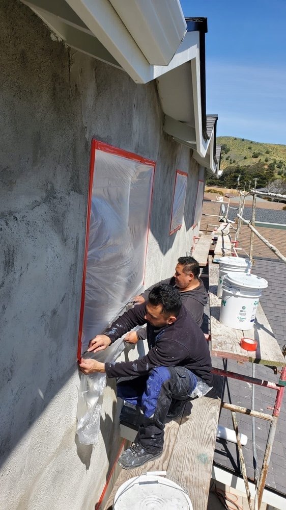 Crew sealing a window opening on a stucco exterior wall