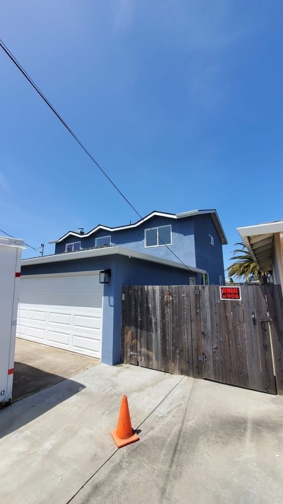 Blue two-story house with a garage and a traffic cone in front