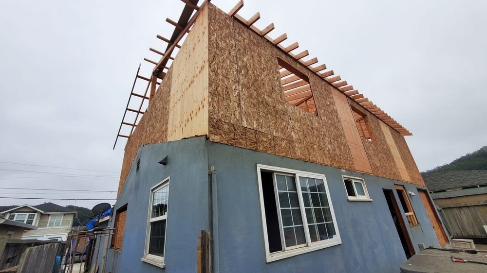 Second-story addition framed and sheathed on a blue house