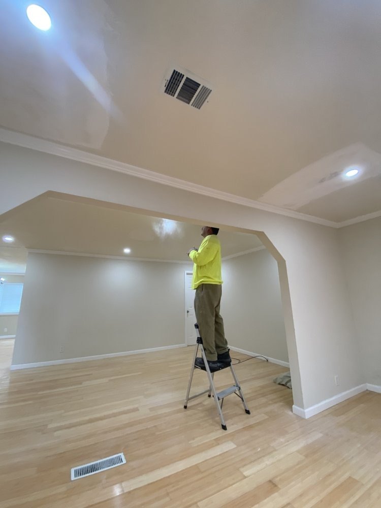 Finished interior with a new hardwood floor and a worker on a ladder
