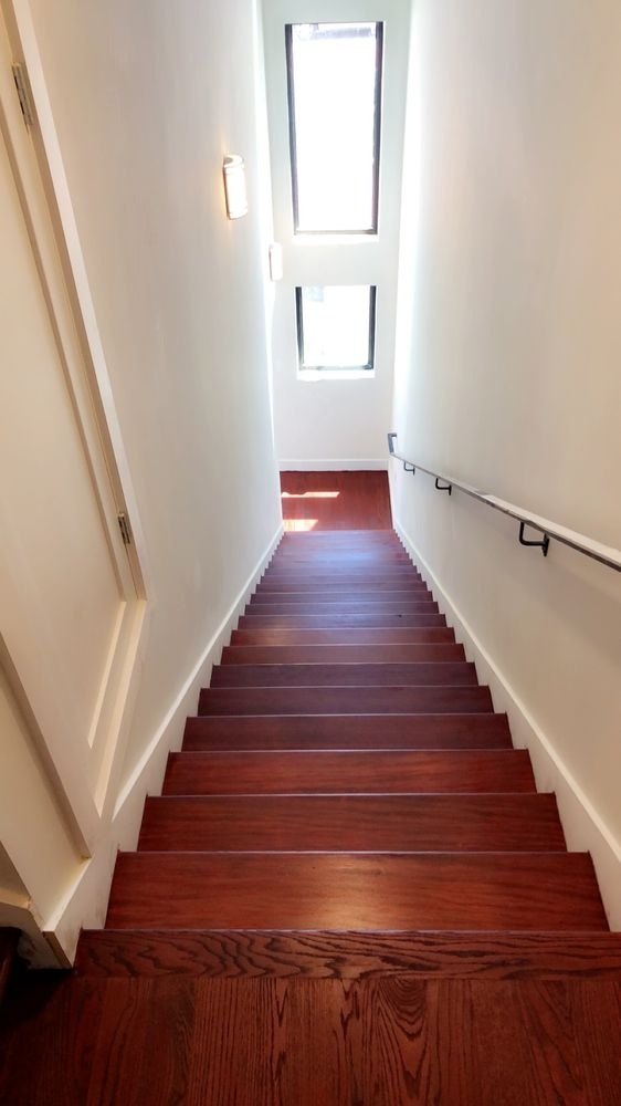Staircase with red-stained treads between white walls