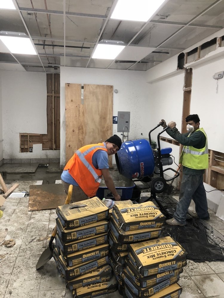 Crew mixing concrete in a gutted commercial space
