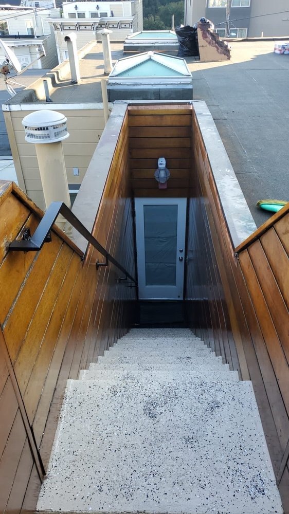 Exterior stairs between wood-clad walls with a door at the bottom