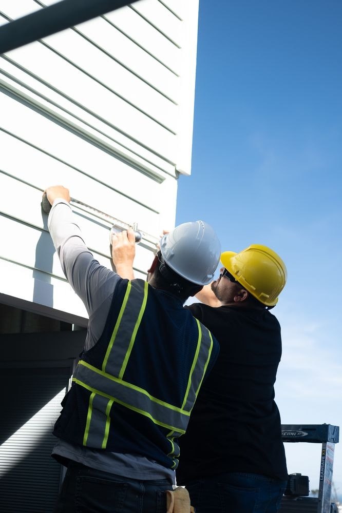 Two workers measuring on a house exterior