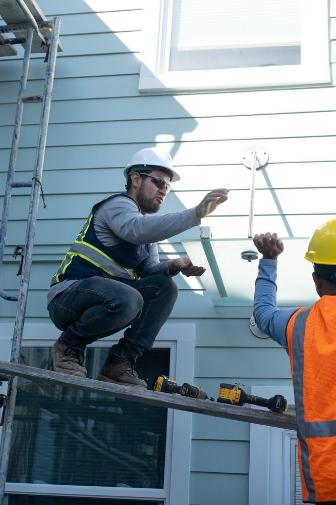 Workers installing a fixture at a house exterior