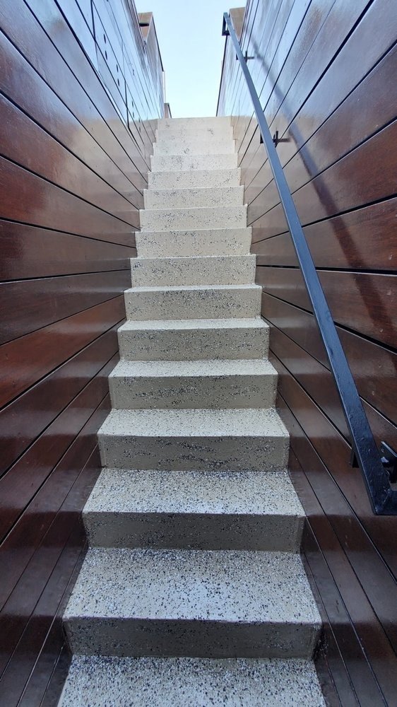 Concrete exterior stairs between wood-clad walls