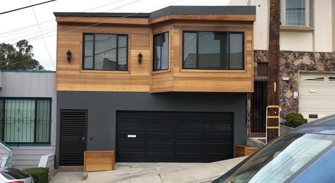 Modern house exterior with cedar siding and a black garage door