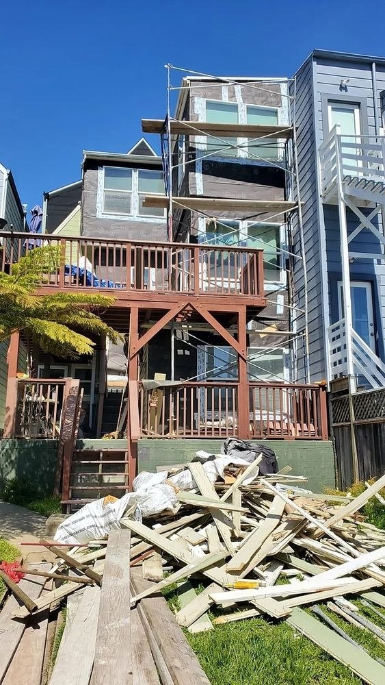 House under renovation behind a deck and scaffolding
